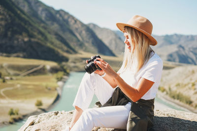 Side view of young woman photographing with mobile phone