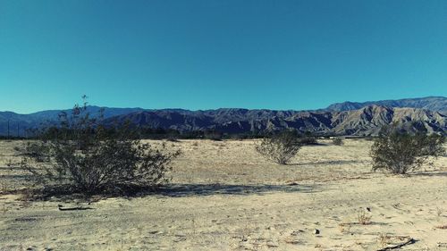 Scenic view of desert against clear blue sky