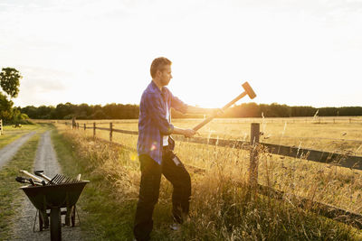 Man hammering fence on grassy field during sunny day