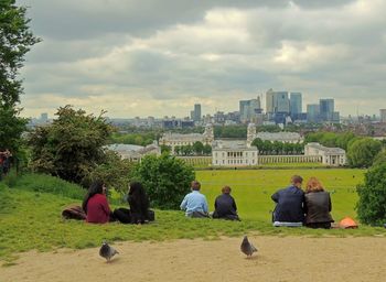 People sitting in park with city in background