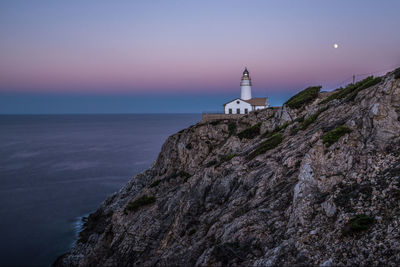 Lighthouse by sea against sky