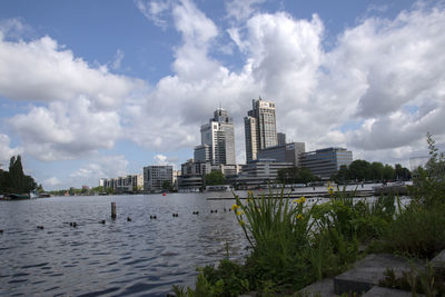 Buildings by river against sky