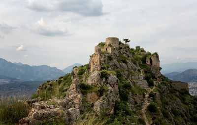 View of cliff on mountain against cloudy sky