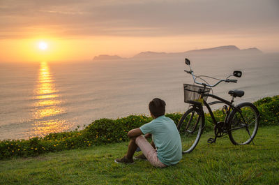 Man sitting on bicycle at sunset