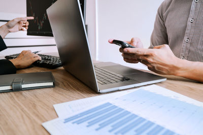 Midsection of man using laptop on table