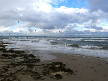 Scenic view of beach against cloudy sky
