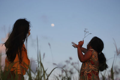 Rear view of girls pointing at sky 