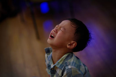 High angle view of cute boy crying on floor at home