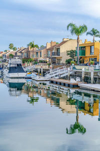 Sailboats in canal by buildings in city against sky