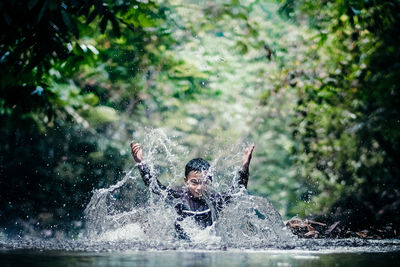 Portrait of boy splashing water while in river