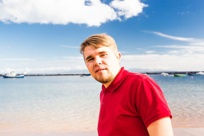Portrait of young man on beach against sky