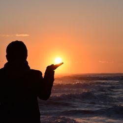 Silhouette man on beach against sky during sunset