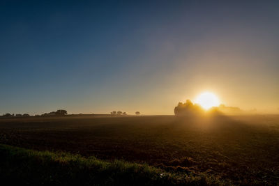 Scenic view of field against clear sky during sunset