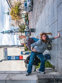 Tilt image of woman performing stunt on sidewalk in city