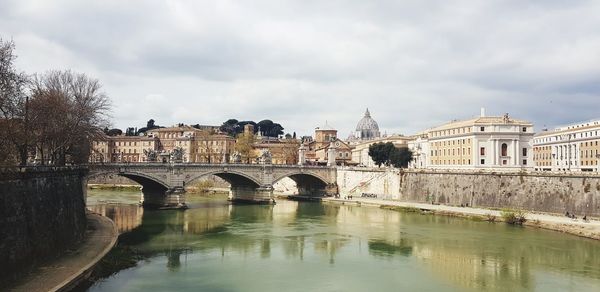Arch bridge over river against buildings in city