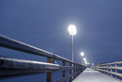 Illuminated pier against sky at night