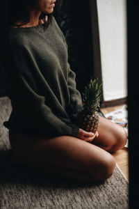 Low section of woman sitting on floor at home