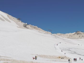 Group of people on mountain road against clear sky