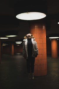 Full length of young woman jumping under illuminated light in garage