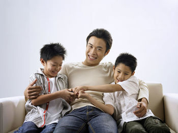 Portrait of smiling man with sons sitting on sofa