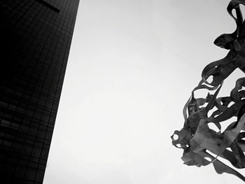 Low angle view of sculpture against building against clear sky