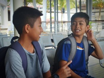 Brothers talking while sitting on chairs