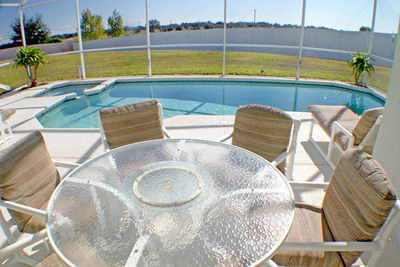 Chairs by swimming pool by sea against sky