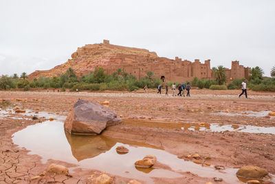 People on rock against sky