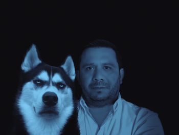 Portrait of man with dog against black background