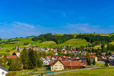 Houses amidst trees and buildings against blue sky