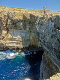 Man standing on cliff against sky