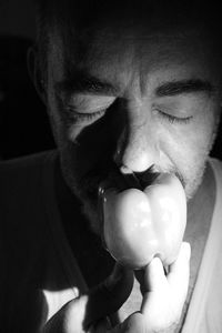 Close-up of man smelling bell pepper