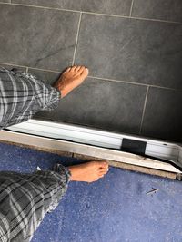 Low section of man standing on tiled floor