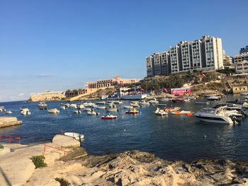 Boats in sea with buildings in background