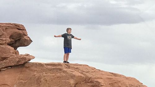 Full length of man standing on rock against sky