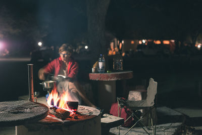 Woman preparing food in yard at night