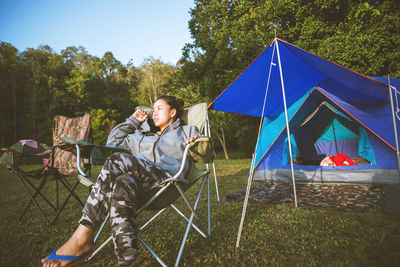 Man sitting in tent on field against sky