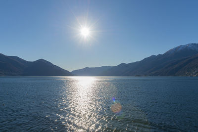Scenic view of lake and mountains against clear blue sky