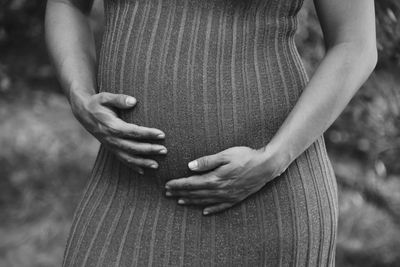 Midsection of woman with arms raised standing outdoors