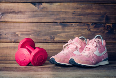 Close-up of pink shoes and dumbbells on wooden floor