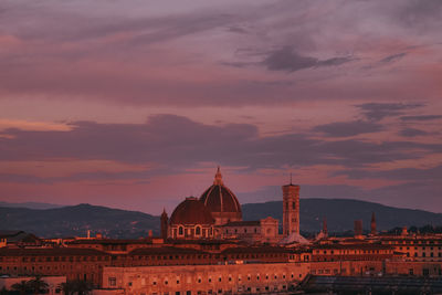 Buildings in city against cloudy sky during sunset