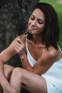 Beautiful young woman looking down while sitting outdoors