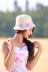 Midsection of woman wearing hat standing against blurred background