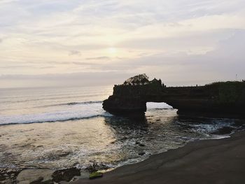 Rock formation on beach against sky