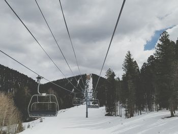 Ski lift over snow covered road against sky