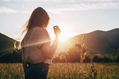 Side view of woman standing on field during sunset