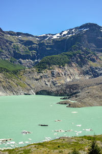 Scenic view of lake by mountain against blue sky