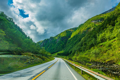 Road amidst green mountains against sky