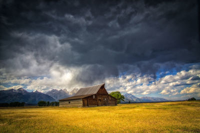 Built structure on field against storm clouds