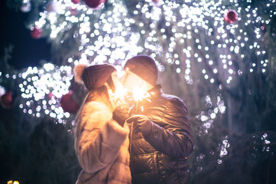 People in illuminated christmas tree at night